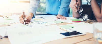 A man and a woman make notes on charts and graphs.